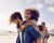 Group of friends walking along the beach, with men giving piggyback ride to girlfriends. Happy young friends enjoying a day at beach.